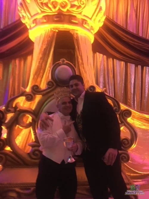 Two guests posing beside a Mardi Gras throne